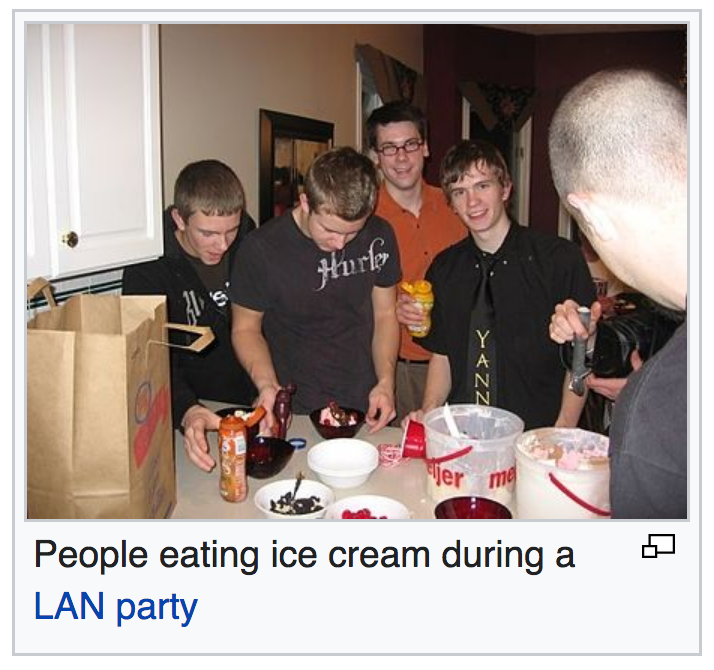 screenshot of an image on wikipedia of a few guys standing around a table with ice cream on it with the caption 'people eating ice cream at a lan party'